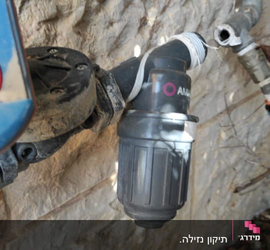 צינור מים עם מחבר פלסטיק על קיר אבן
